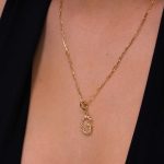 Woman wearing gold letter pendant on a necklace.