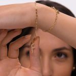 Woman wearing gold letter F pendant on a bracelet.