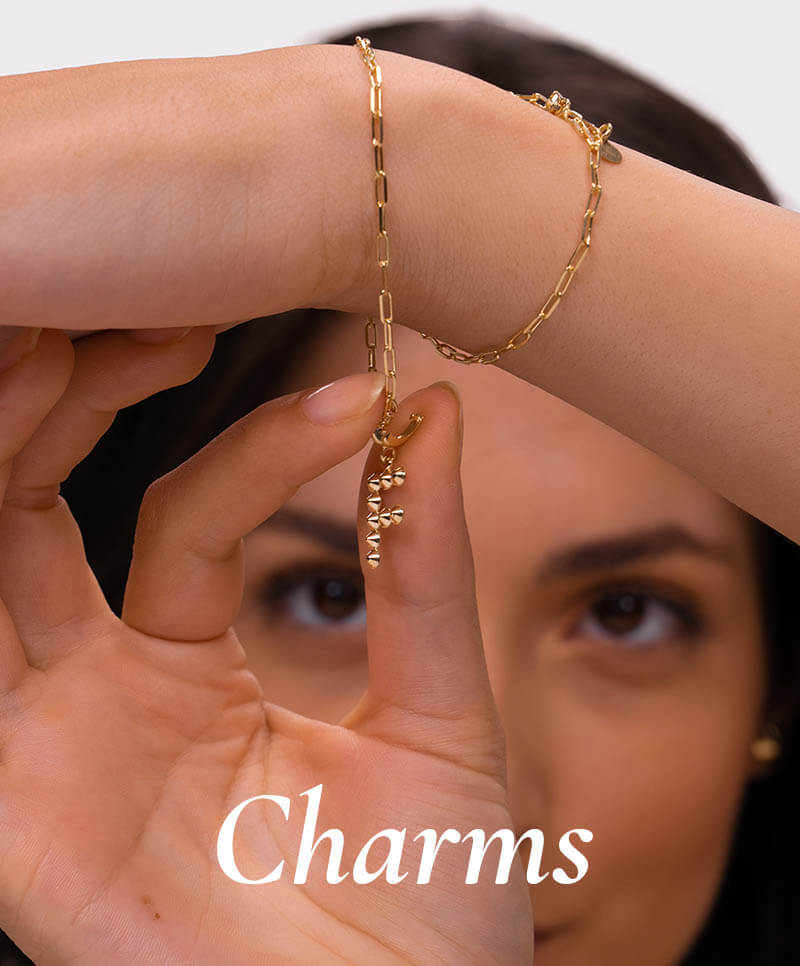 Woman wearing gold letter F pendant on a bracelet.